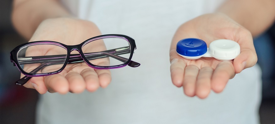 someone holding a contact lenses case in one hand and a pair of glasses in the other hand