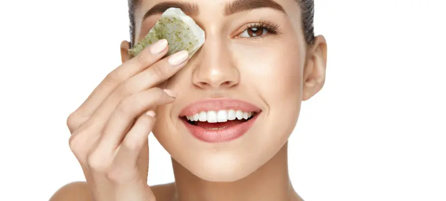 Woman holding a tea bag against her eye