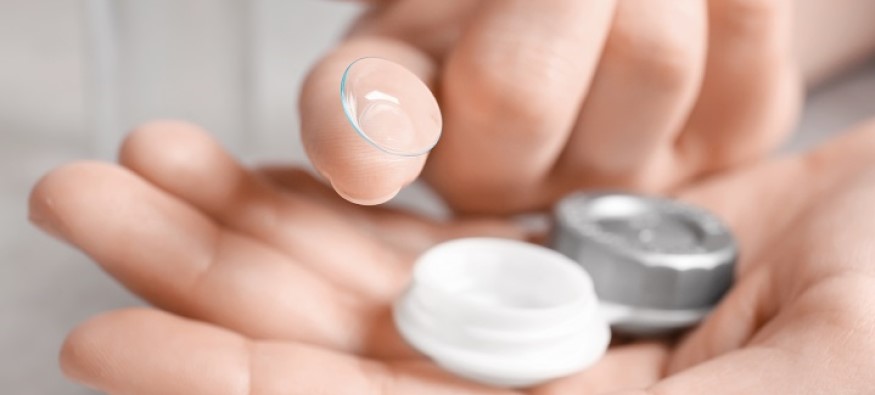 a pair of hands holding contact lenses
