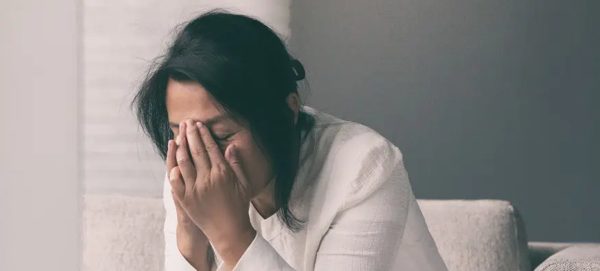 woman looking stressed with her hands up to her face